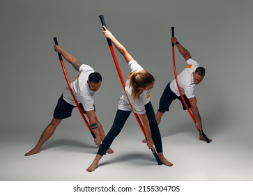 Two men and woman aikido fighters with wooden fight stick posing in studio, fight demonstration