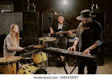 Two men and woman playing bass guitar, synthesizer and drums in rock band, copy space - Powered by Shutterstock