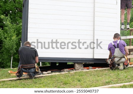 Two men are working on installing a gazebo in the garden, hired workers at work.