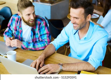 Two Men Working On Laptop At Coffee Shop