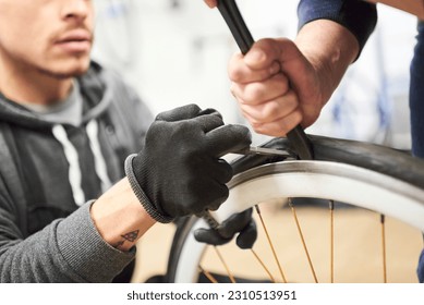 Two men working together collaboratively to remove an airless tire from a bicycle wheel at a bike repair shop. Selective focus composition with copy space. - Powered by Shutterstock