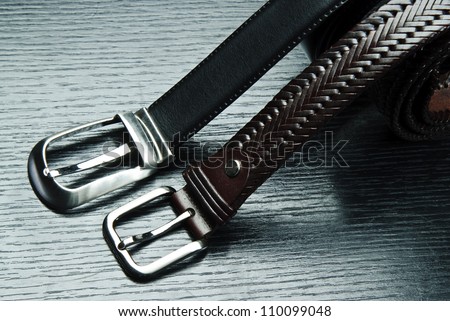Two men's belts on grey background.