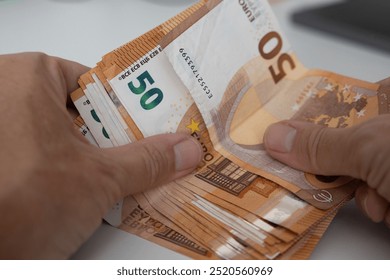 Two men's hands and a stack of 50 Euro notes