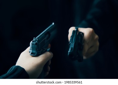 Two Men's Hands With Weapons Pointed At Each Other. Shootout With Firearms Of Two Criminals On Dark Background. Killer With Gun. Detective With A Revolver.