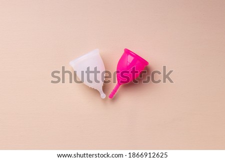 Two menstrual cups on beige background top view