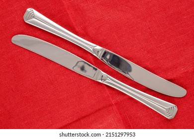 Two Metal Knives On A Red Linen Napkin, Macro, Top View.