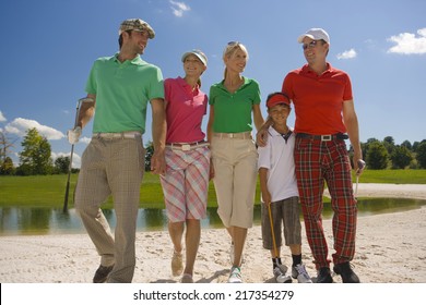 Two mid adult couples with a boy walking on the sand trap on a golf course