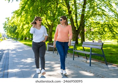  Two mid-adult beautiful women walking and talking in city park  - Powered by Shutterstock