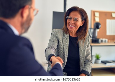 Two middle age business workers smiling happy and confident. Working together with smile on face shaking hands at the office - Powered by Shutterstock