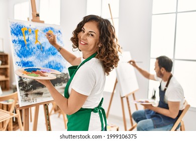 Two Middle Age Student Smiling Happy Painting At Art Studio.