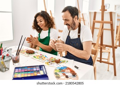 Two middle age students smiling happy modeling clay sitting on the table at art school. - Powered by Shutterstock