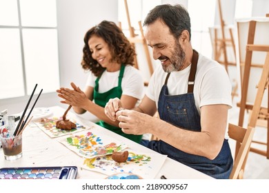 Two middle age students smiling happy modeling clay sitting on the table at art school. - Powered by Shutterstock