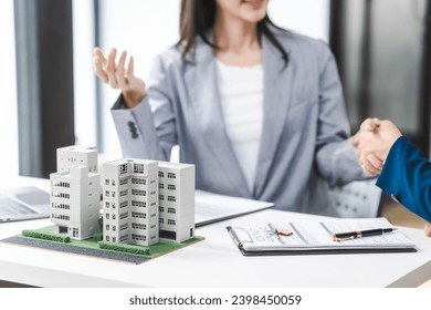 Two middle aged and young Asian business woman in formal suits discuss over model buildings, on city investment and development strategies. urban investment opportunities in city, condo, apartment. - Powered by Shutterstock