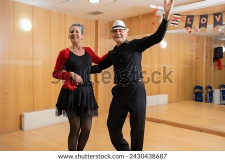 two middleaged older couple dancing in a hall with light strings