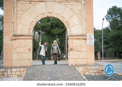 Two middle-aged women exploring historic archway in a Spanish village - Powered by Shutterstock