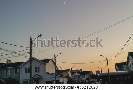 two military fighter fly on background of the moon crescent. condensation trail illuminated rays of the setting sun. country village.