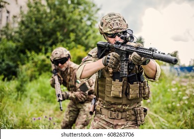 Two military man snipers with airsoft automatic rifle  with a telescopic sight lies in grass in forest. Focus on rifle of first man