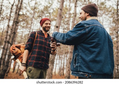 Two Millennial Man Hiking And Drinking Beer In A Pine Forest, Laughing And Having Fun.