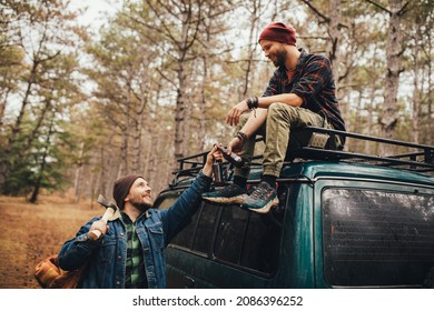 Two Millennial Man Hiking In A Pine Forest, Drinking Beer And Having Fun.