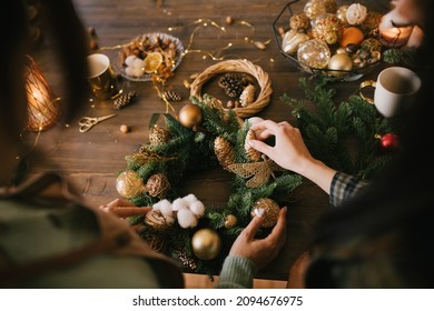 Two millennial women making Christmas wreath using fresh pine branches and festive decorations. Small business