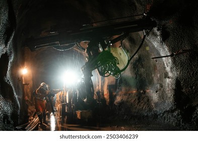 Two miners working in a dimly lit underground tunnel with mining equipment - Powered by Shutterstock