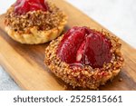 Two mini tarts with a red fruit filling and a nut topping.