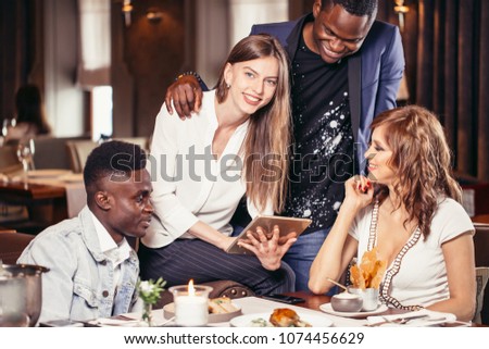 Two mixed couples having a good time at restaurant talking about future vacations