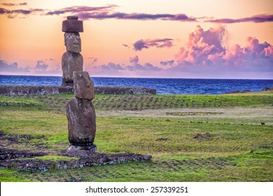 Two Moai Statues On Easter Island With A Purple Sunset Behind Them