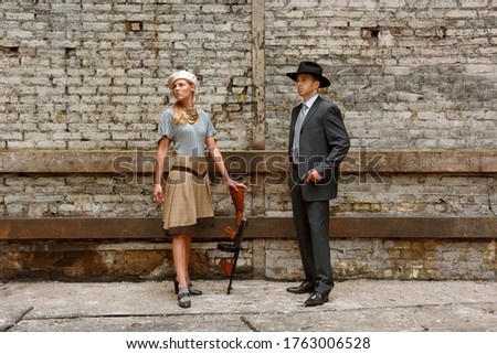 Two models get dressed up in 1930's style vintage 
clothing and act the part of the gangster duo 
Bonnie and Clyde. They are seen in the ruins of an 
old demolished factory.