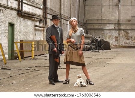 Two models get dressed up in 1930's style vintage 
clothing and act the part of the gangster duo 
Bonnie and Clyde. They are seen in the ruins of an 
old demolished factory.