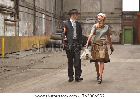 Two models get dressed up in 1930's style vintage 
clothing and act the part of the gangster duo 
Bonnie and Clyde. They are seen in the ruins of an 
old demolished factory.