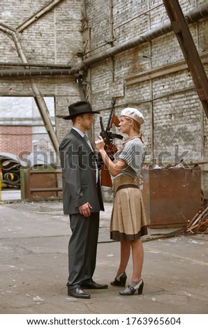 Two models get dressed up in 1930's style vintage 
clothing and act the part of the gangster duo 
Bonnie and Clyde. They are seen in the ruins of an 
old demolished factory.
