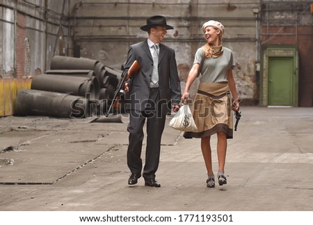 Two models get dressed up in 1930's style vintage 
clothing and act the part of the gangster duo 
Bonnie and Clyde. They are seen in the ruins of an 
old abandoned factory.