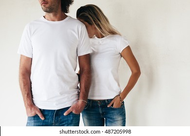 Two models man and woman wearing blanc t-shirt posing against white wall, toned photo, front tshirt mockup for couple