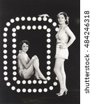 Two models posing by large letter O