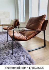 Two Modern Brown Leather And Metal Armchairs In Living Room With White Walls And Gray Shag Rug