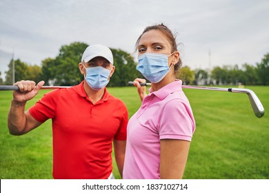 Two modern golfers in disposable face masks and polo shirts standing on the golf course - Powered by Shutterstock