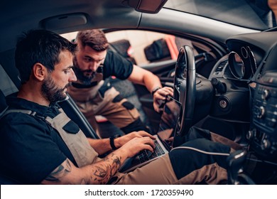 Two modern mechanics doing diagnostic in the car. Concept of work.