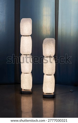 Two modern standing lamps featuring stacked translucent modules creating artistic illumination