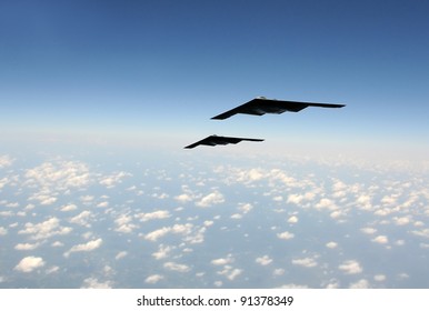 Two modern stealth bombers flying at high speed