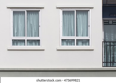 Dos ventanas modernas con cortina de protección uv en pared blanca, vista exterior