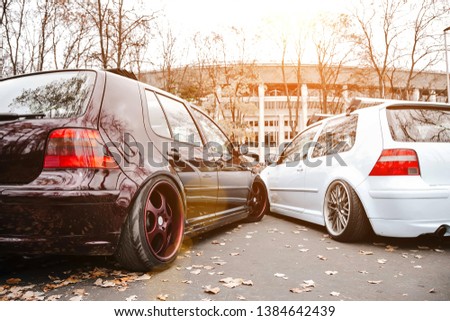 Two modified low cars in brown and light blue color. Stance custom cars with a forged polished wheels parked on a street at sunny day. Tuned automobiles with air suspension