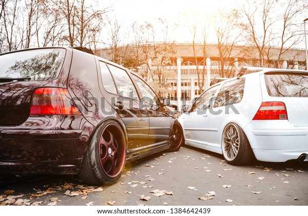 Two modified low\
cars in brown and light blue color. Stance custom cars with a\
forged polished wheels parked on a street at sunny day. Tuned\
automobiles with air\
suspension