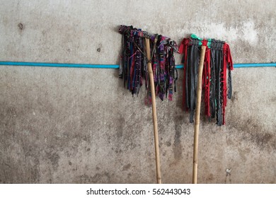 The two mop lean on the dirty concrete wall