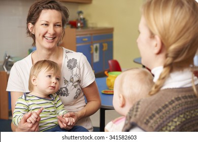 Two Mothers With Children Chatting At Playgroup