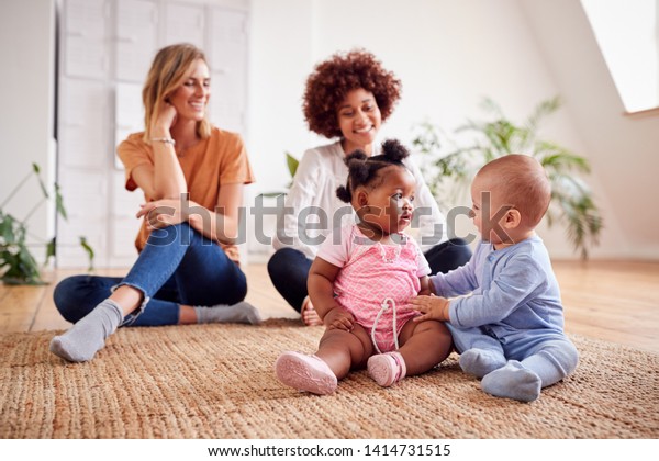 Two Mothers Meeting For Play Date With Babies\
At Home In Loft Apartment