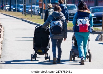 Two mothers with prams and backpacks walk with children around the city - Powered by Shutterstock