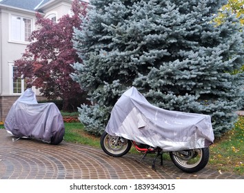 Two Motor Bikes In Driveway Covered With Grey Tarp. Preparation For Winter