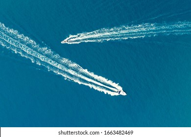 Two motor boats with a Wake behind them on a turquoise background of the sea surface. Shooting from a drone.