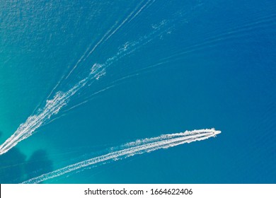 Two Motor Boats With A Wake Behind Them On A Turquoise Background Of The Sea Surface. Shooting From A Drone. The View From The Top.